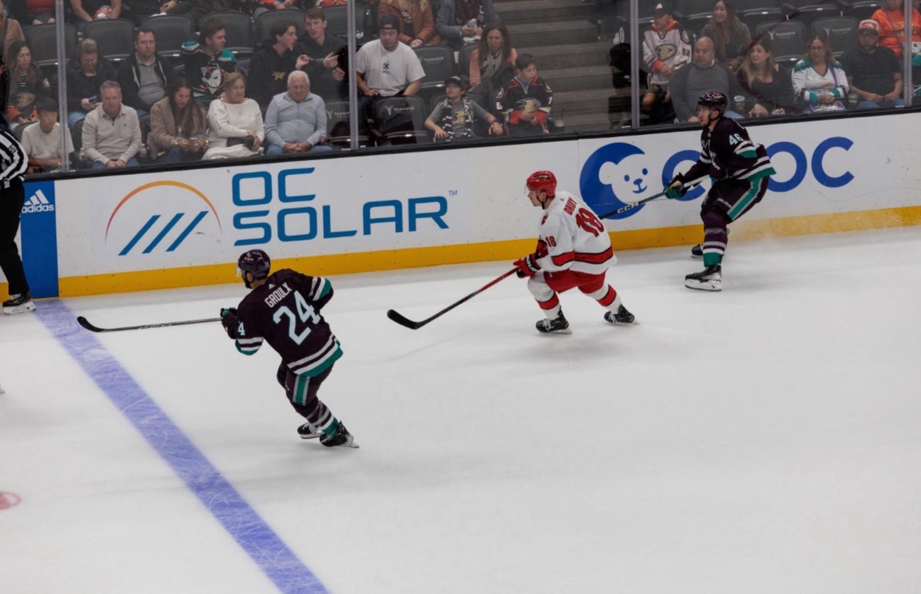 The OC Solar logo on the Honda Center dasher boards behind live Anaheim Ducks game action
