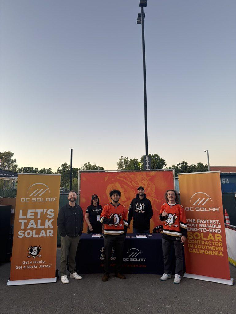 OC Solar's 'Let's Talk Solar' booth at Honda Center — 'Get a Quote, Get a Ducks Jersey' banner with the team