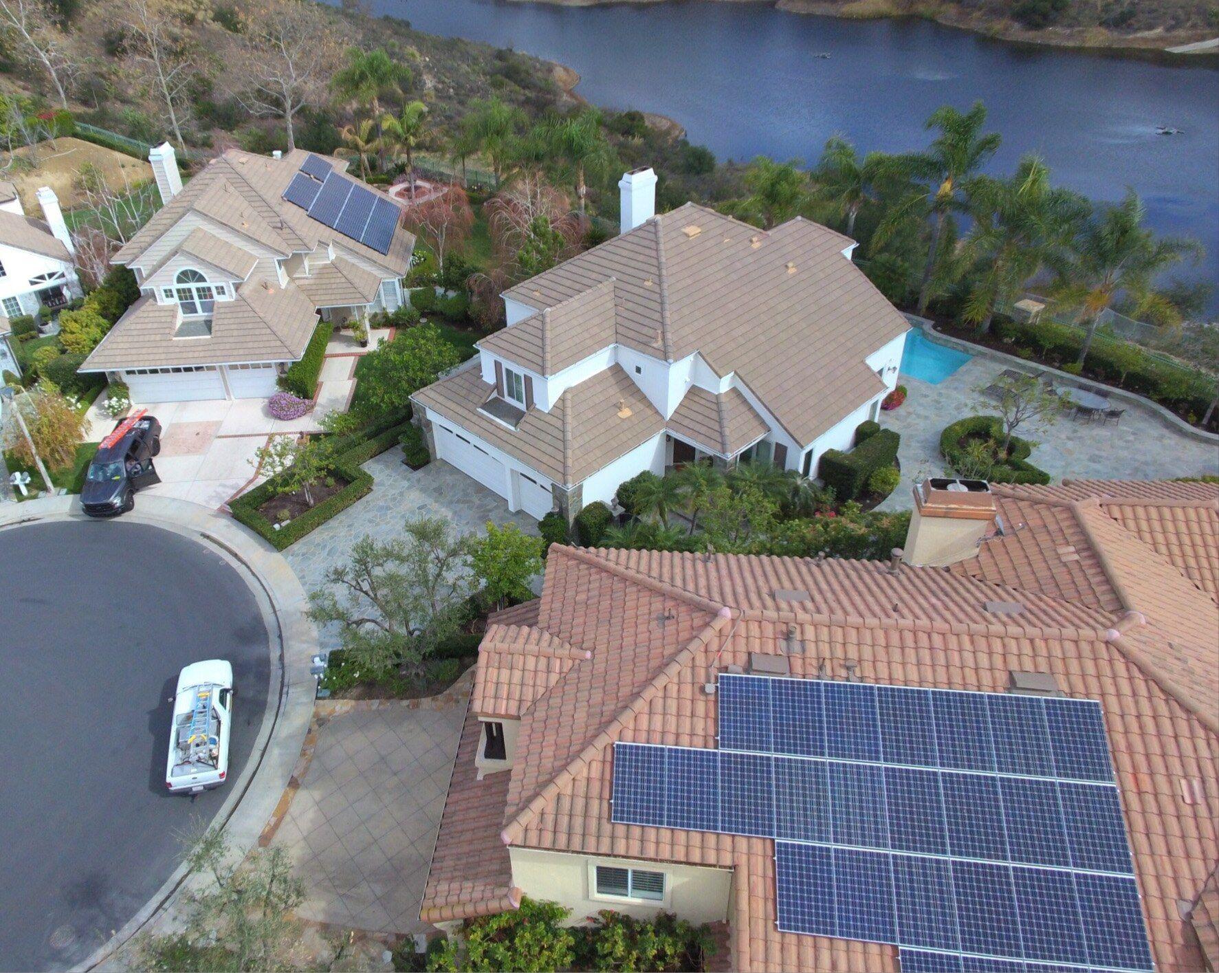 Aerial view of two neighboring Southern California homes on a lakeside cul-de-sac, both with OC Solar rooftop panel arrays