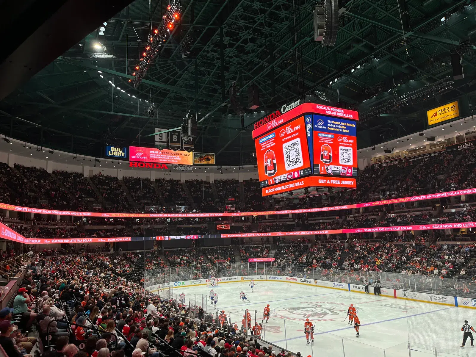 Interior of Honda Center arena during a Ducks hockey game with a crowd and an OC Solar ad on the scoreboard.