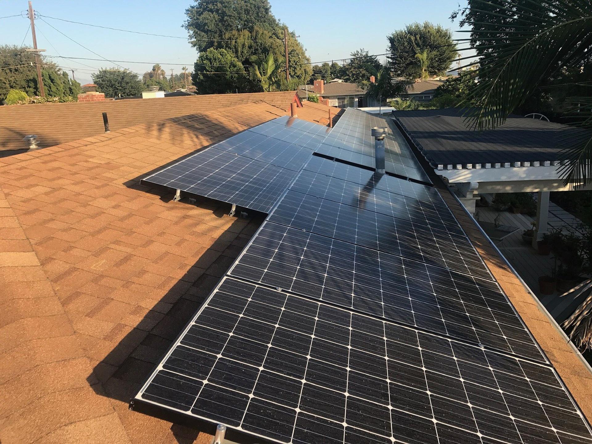 Close drone view of a large all-black solar panel array installed across a shake roof in Southern California