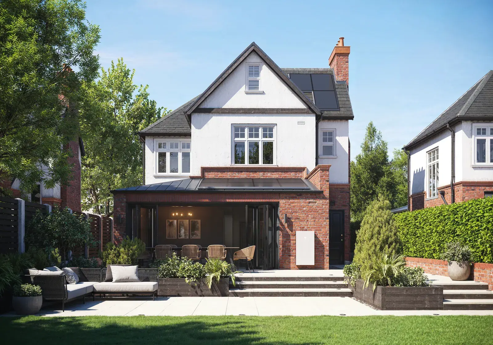 A white Tesla Powerwall on the rear wall of a two-story home beside a patio, with solar panels on the roof above.