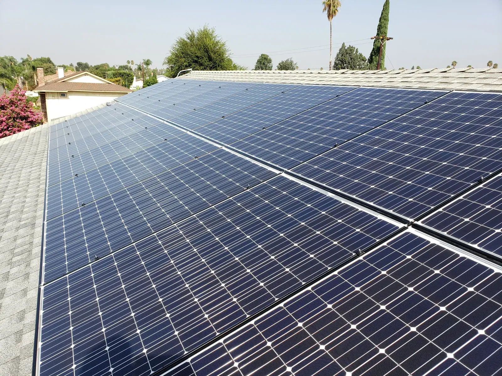 Close-up of blue monocrystalline solar panels mounted on a residential roof under a clear sky.