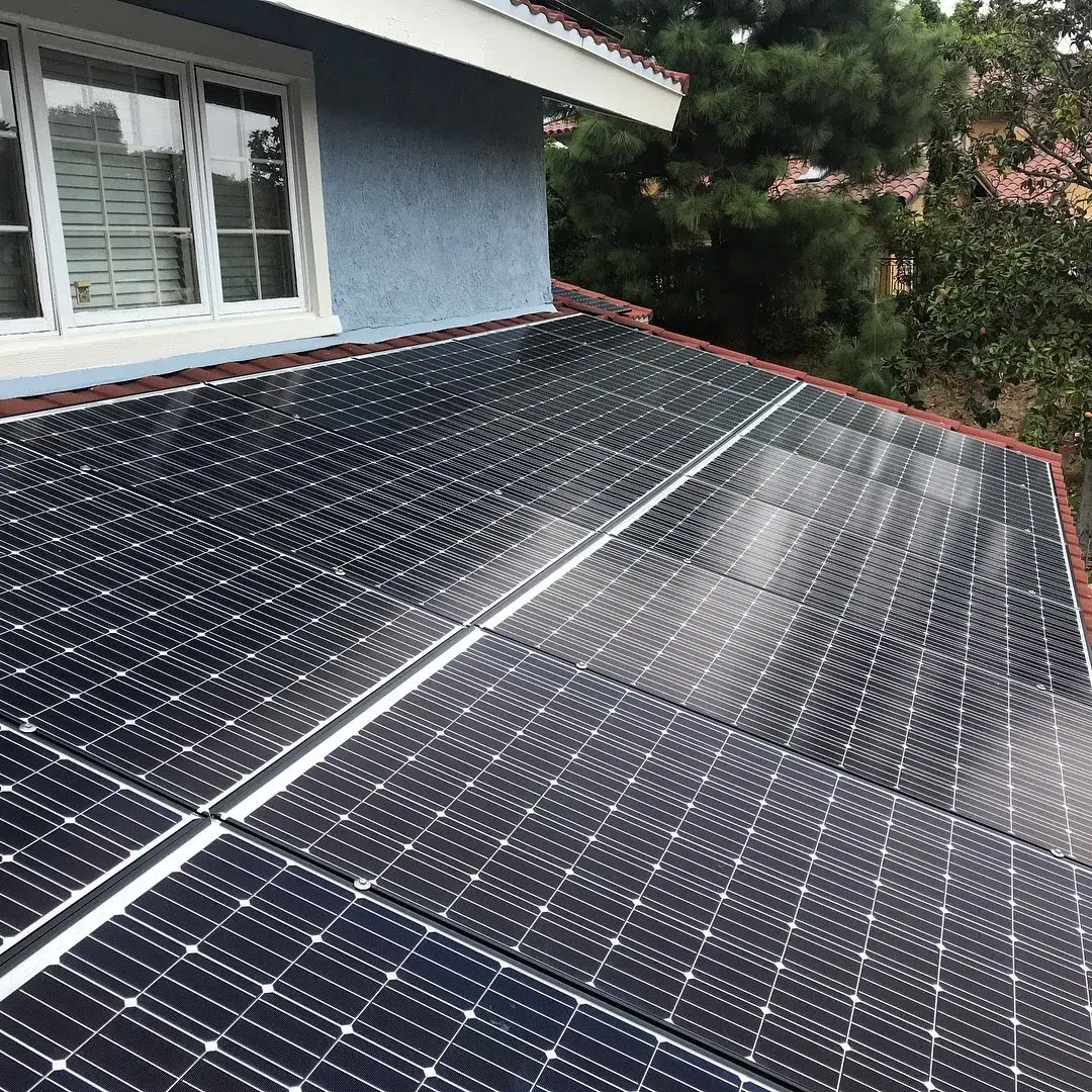Finished rooftop solar panel array installed alongside a home's window and tiled roof edge.