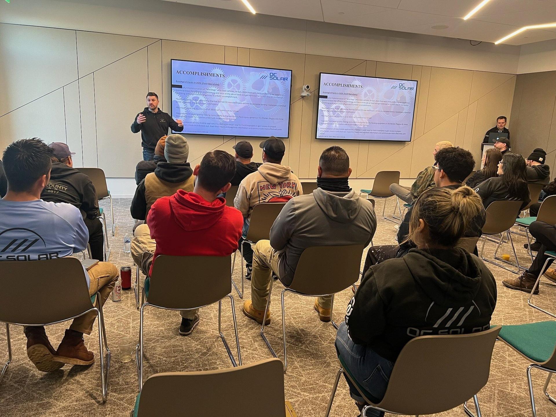 OC Solar team members seated for an installer training session in front of presentation screens at the Irvine headquarters