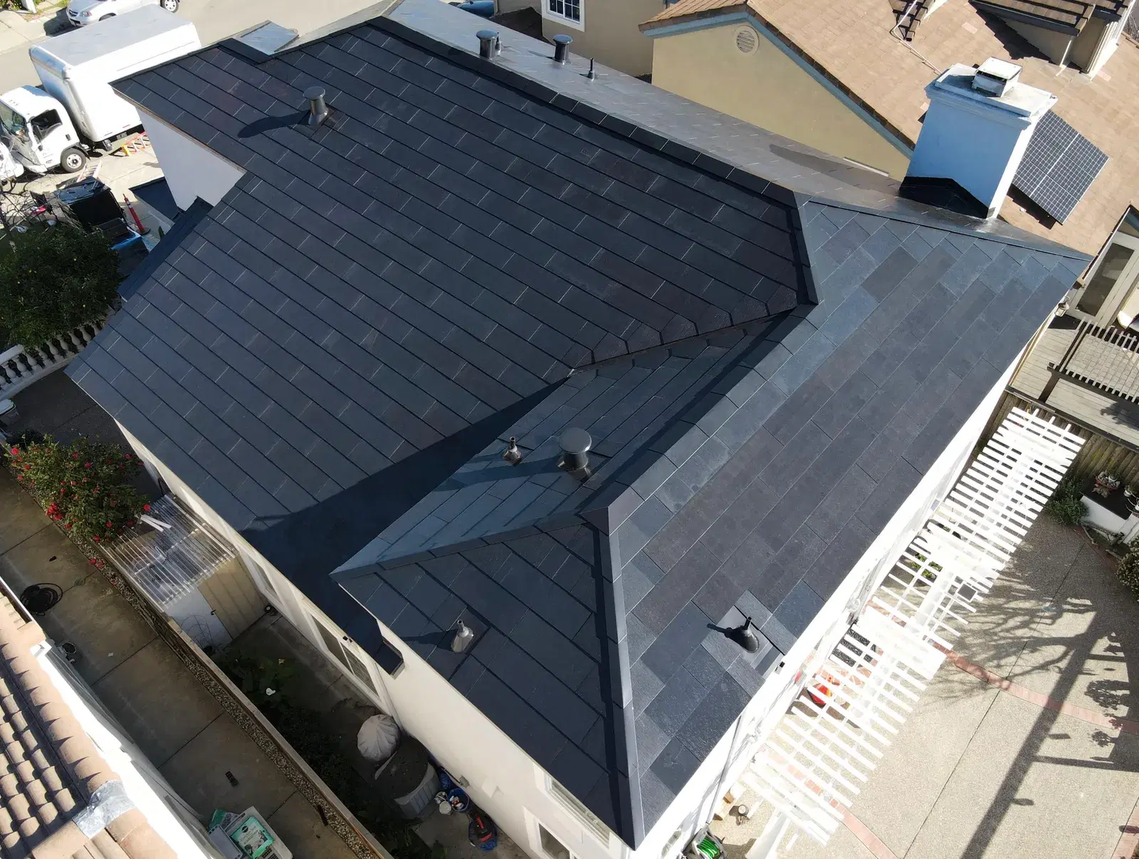 Drone shot looking down on a home roofed entirely in dark gray Tesla Solar Roof glass tiles.