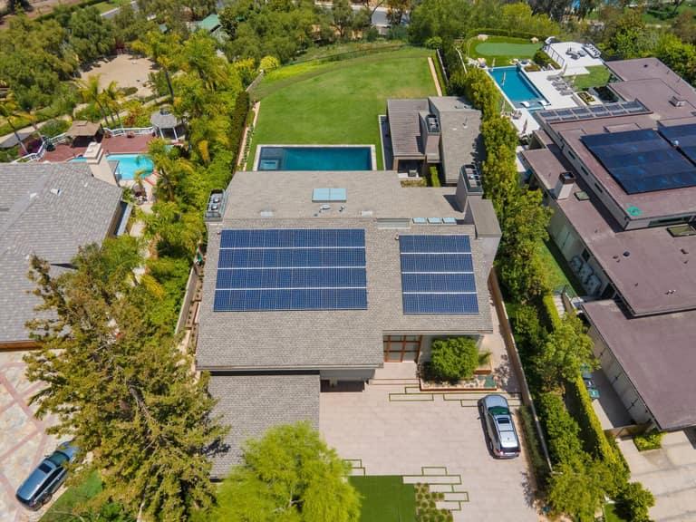 Aerial view of a Southern California estate with an OC Solar rooftop array overlooking a large resort-style backyard pool