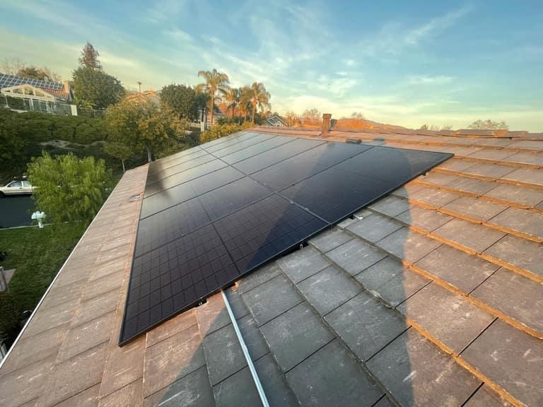 An all-black OC Solar panel array on a Southern California rooftop glowing at golden hour