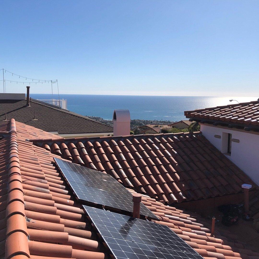 Solar panels on a terracotta tile roof in Orange County overlooking the Pacific horizon