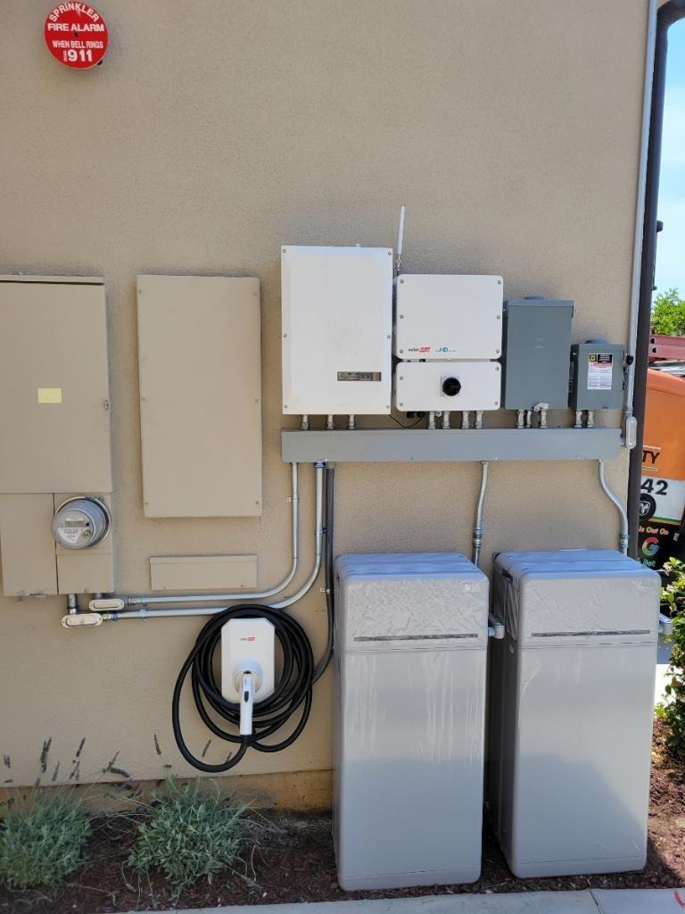 A wall-mounted solar inverter, EV charger, and home batteries on a Southern California home