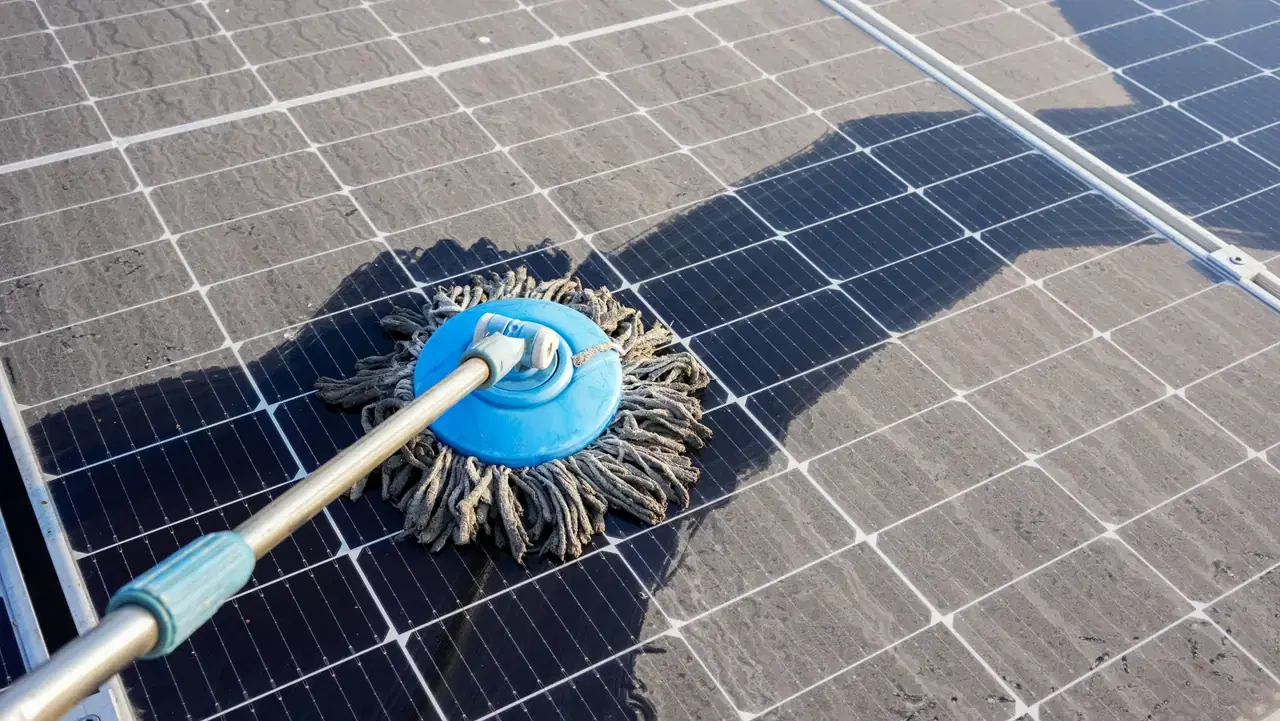 A technician rinsing soiling off a solar panel during a cleaning