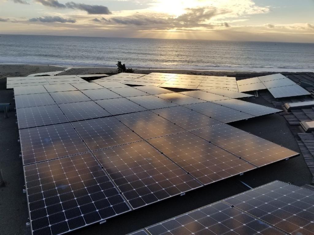Sun rays over an OC Solar panel array above the Pacific at golden hour