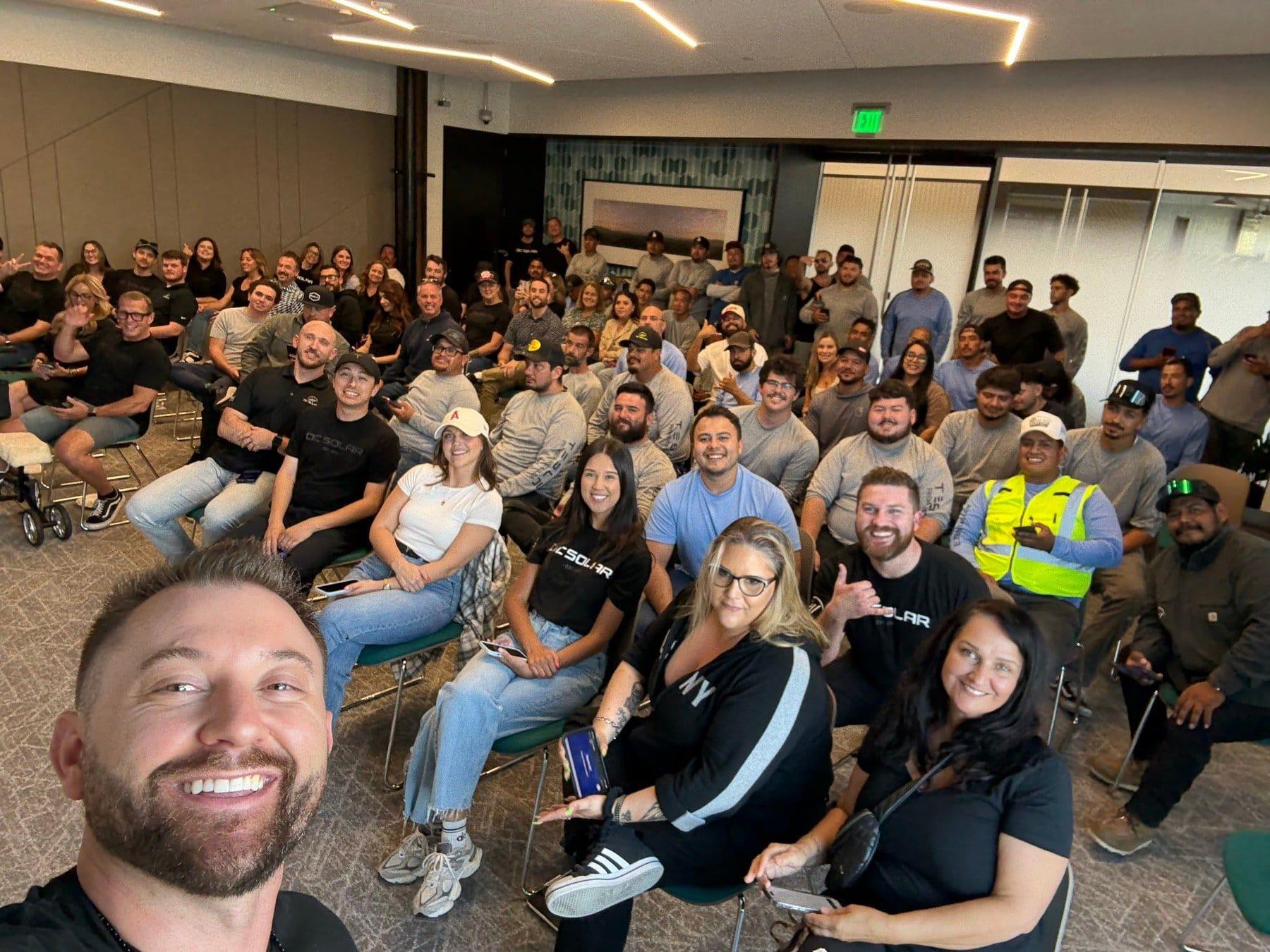 The OC Solar team gathered for a group selfie in the Irvine office, everyone smiling at the camera