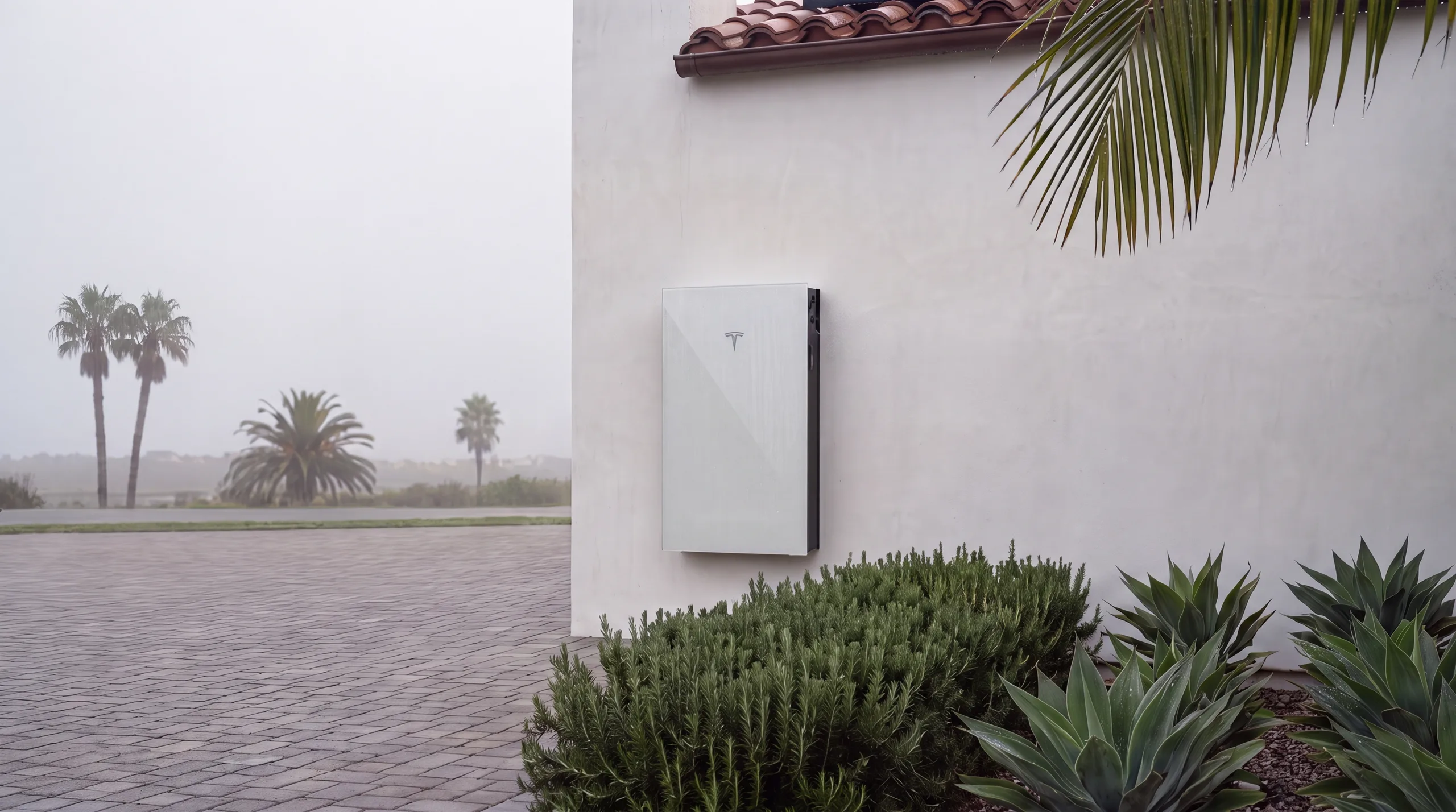 Dawn dew on the sealed face of a Tesla Powerwall 3 against white stucco