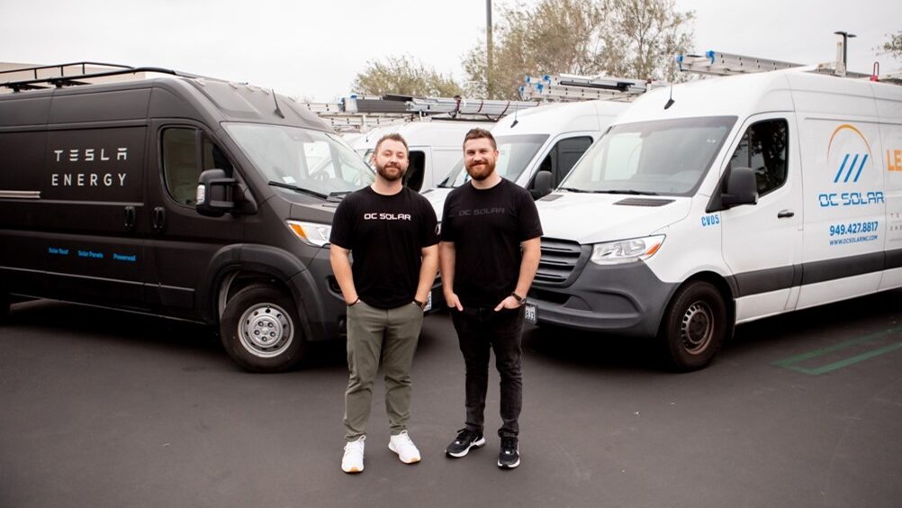 OC Solar team standing in front of OC Solar and Tesla vehicles
